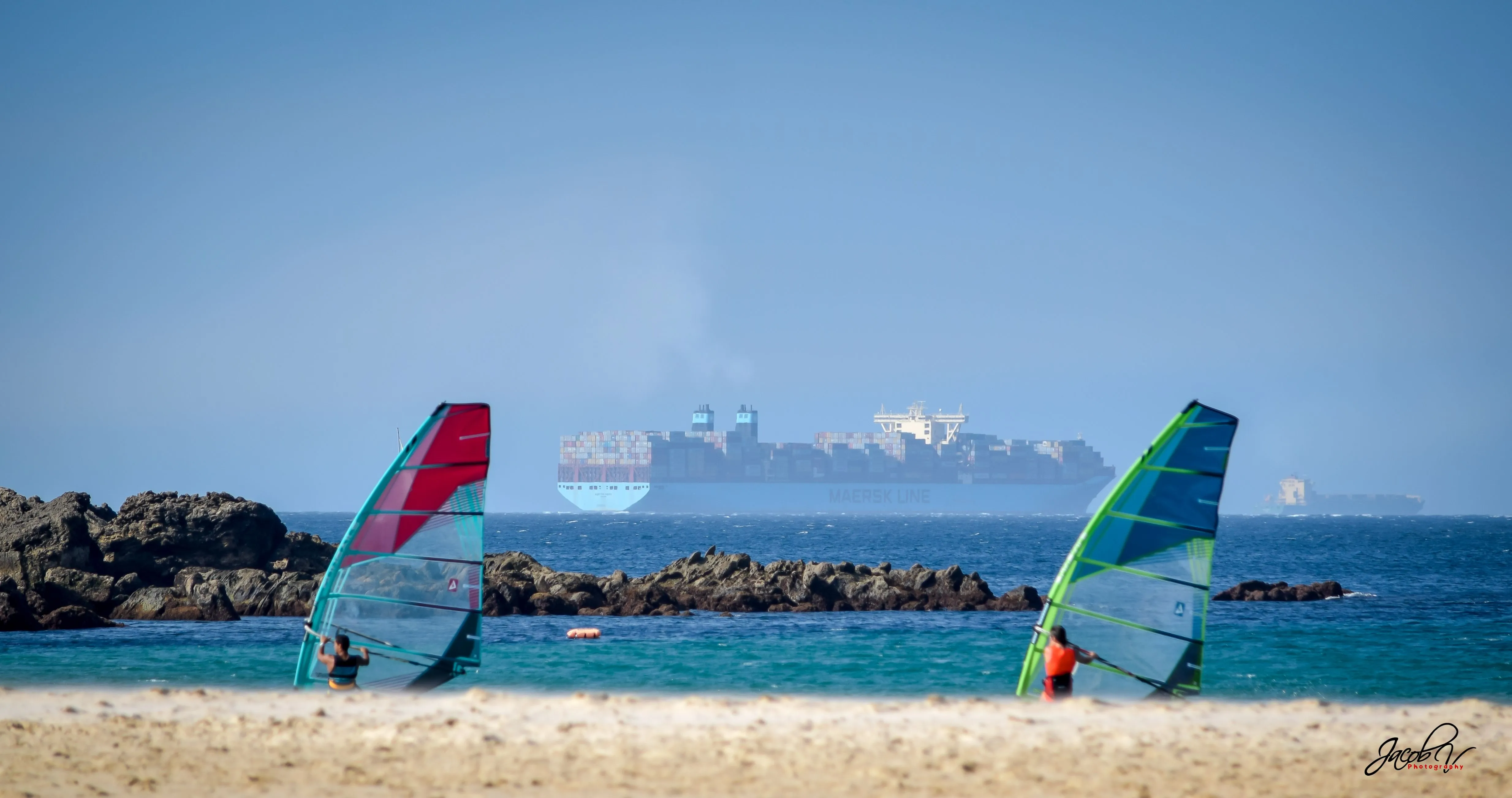 Windsurfistas junto a las rocas con el Estrecho detrás